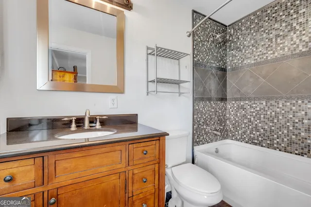 a bathroom with a granite countertop toilet sink and mirror