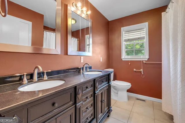 a bathroom with a granite countertop sink a toilet and a mirror