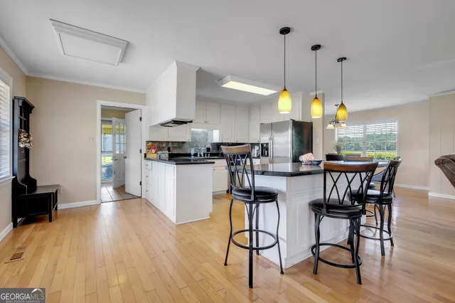 a kitchen with stainless steel appliances granite countertop wooden floor dining table chairs and view living room