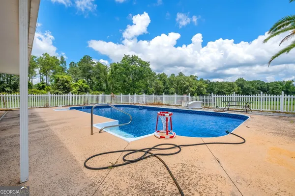 a view of swimming pool with seating space and wooden fence