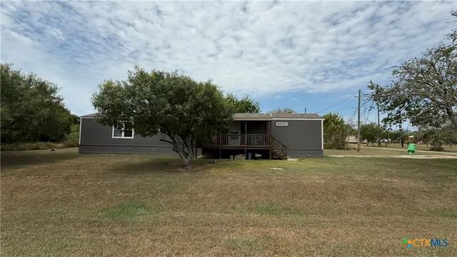a view of a house with backyard and trees