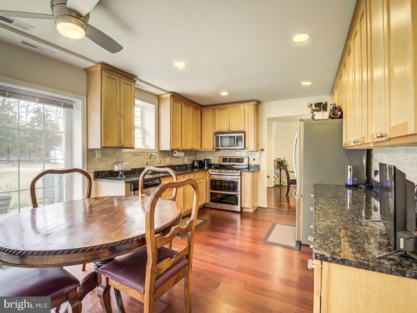 19400 White Ground Road Boyds, MD 20841 - Photo 20 of 59 a kitchen with granite countertop a table chairs microwave and cabinets