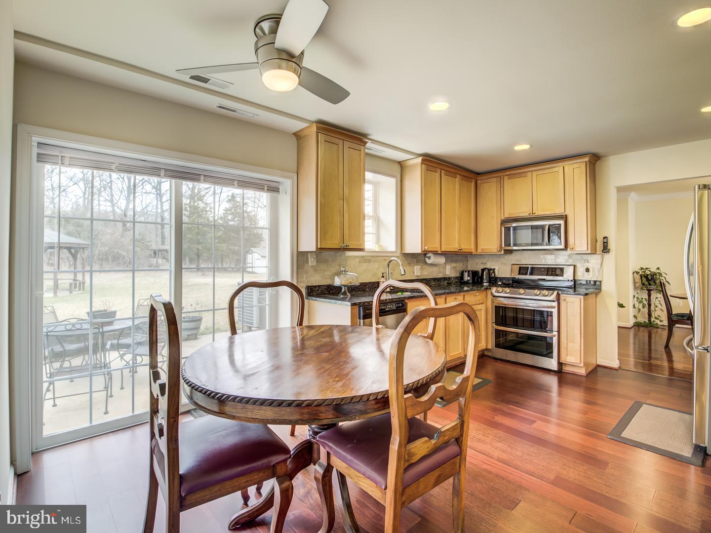 19400 White Ground Road Boyds, MD 20841 - Photo 21 of 59 a kitchen with granite countertop a stove a refrigerator a dining table and chairs with wooden floor