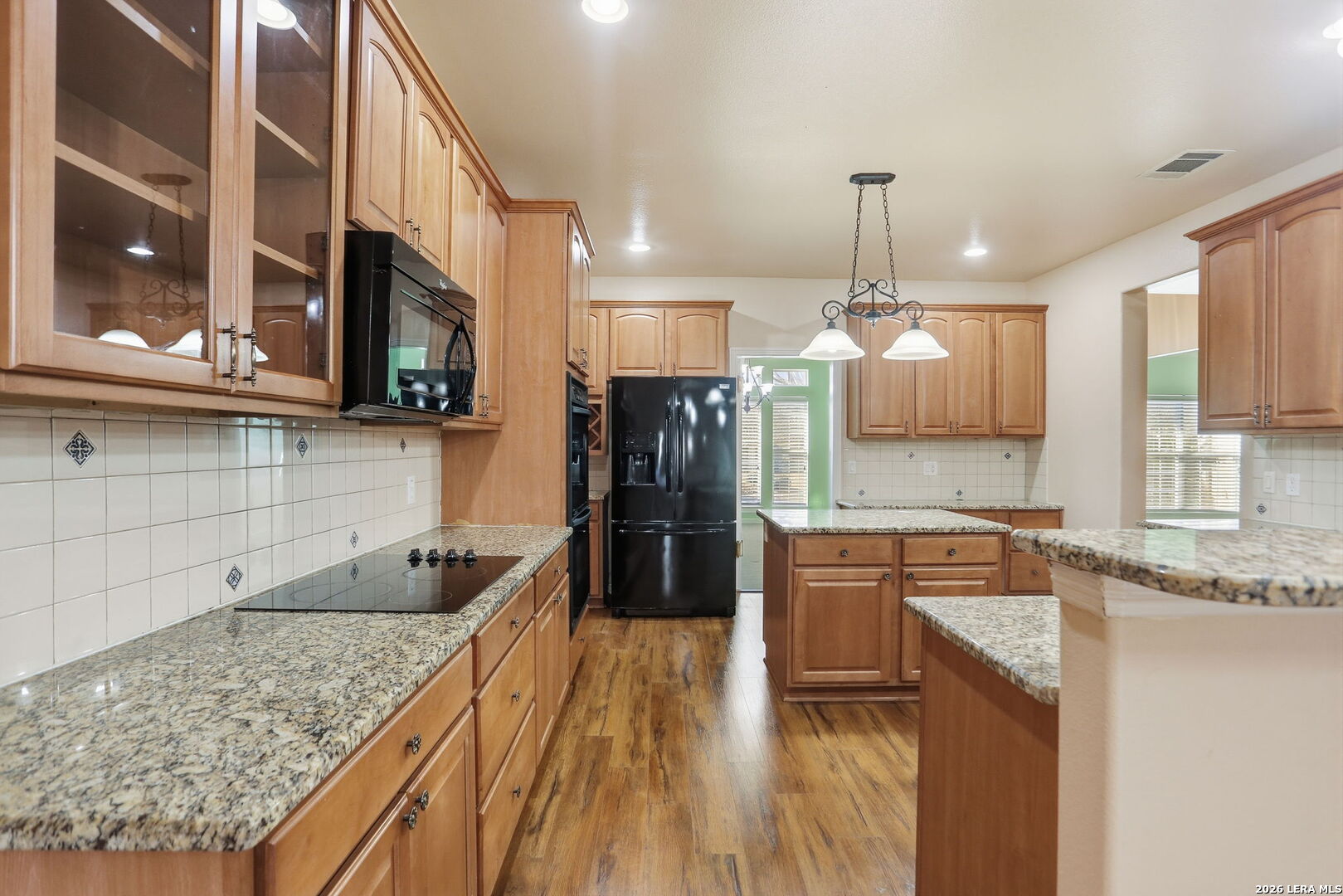 8814 Spanish Moss Windcrest, TX 78239 - Photo 16 of 50 a kitchen with granite countertop a stove a sink a refrigerator and wooden cabinets