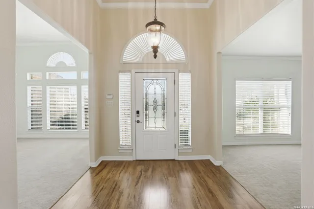 an empty room with wooden floor cabinet and windows