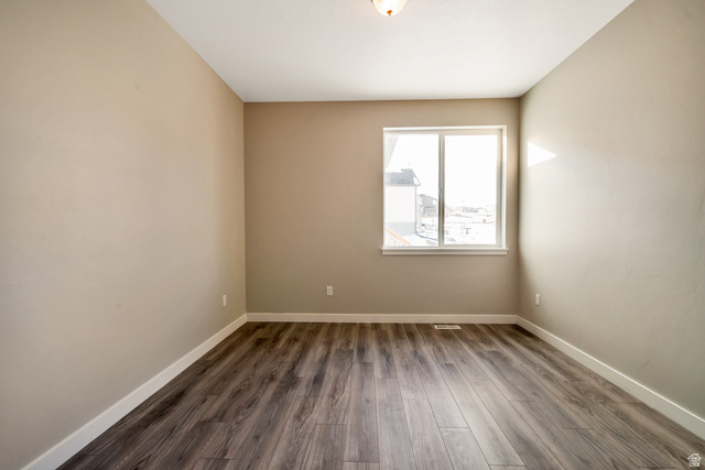 2449 Scarlet Road, Unit 249 Eagle Mountain, UT 84005 - Photo 3 of 26 Bright, light-filled bedroom with expansive window framing natural daylight, neutral wall finishes, wood-finish flooring throughout, and recessed ceiling lighting