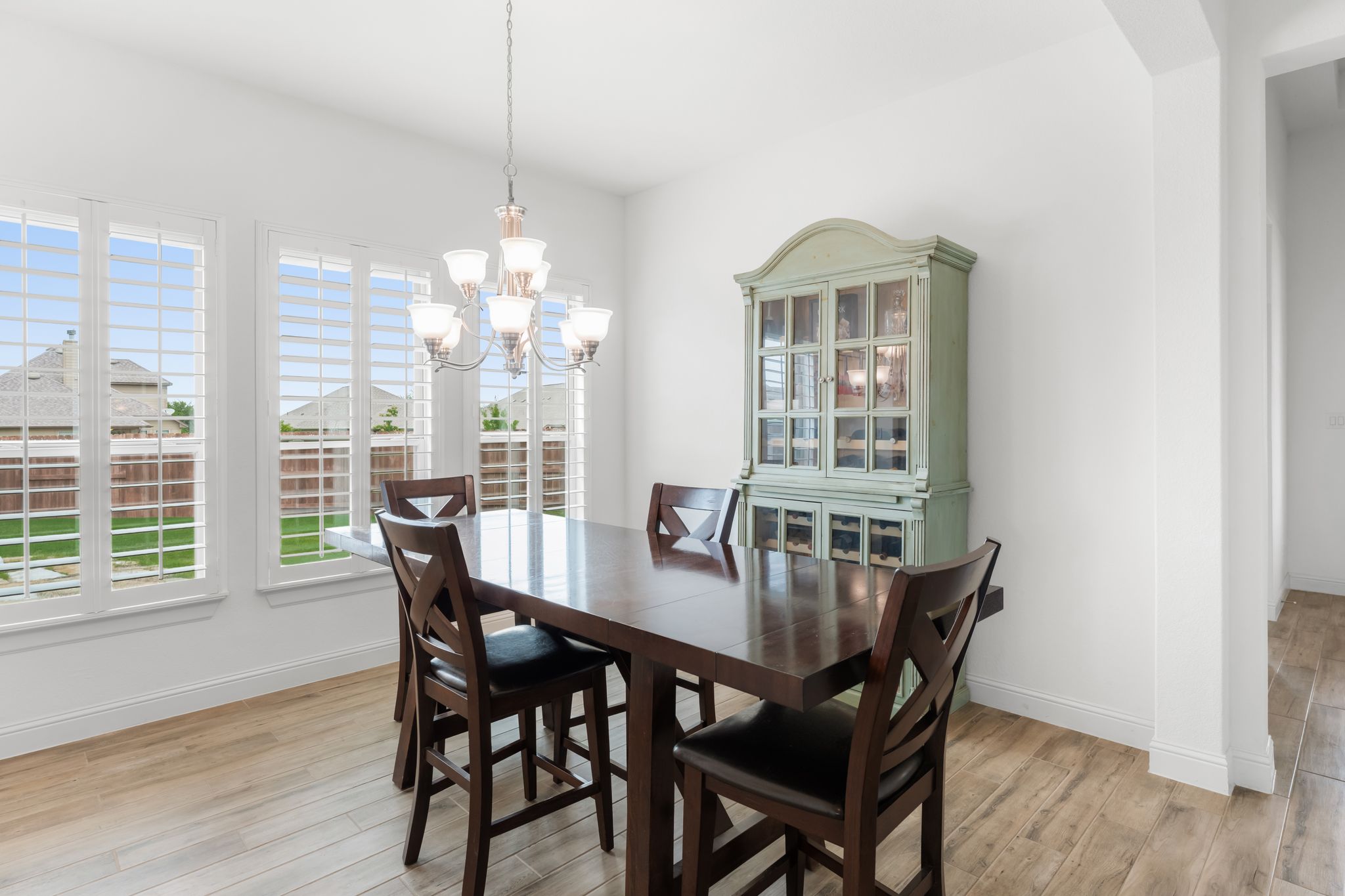 140 Waterloo Cove Georgetown, TX 78628 - Photo 14 of 40 Natural light floods this dining area through multiple windows, illuminating the rich wood-like flooring and elegant chandelier.