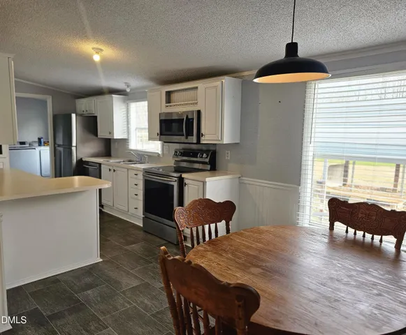 a kitchen with stainless steel appliances granite countertop a stove top oven a sink a dining table and chairs with wooden floor