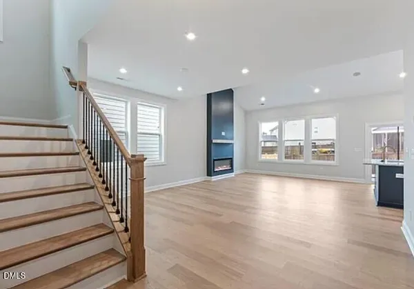 a view of an empty room with wooden floor and staircase