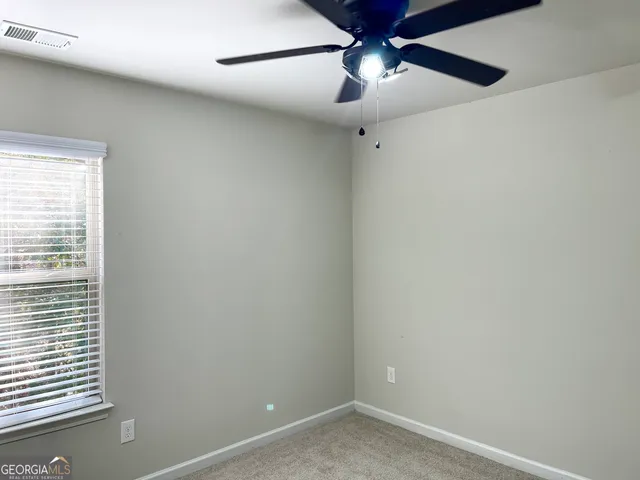 an empty room with a window and a fan