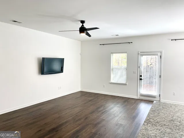 a view of an empty room with wooden floor and a window
