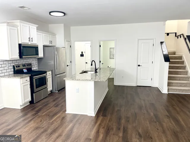 a kitchen with sink a refrigerator and wooden floor