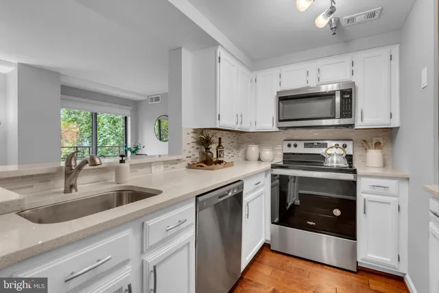 a kitchen with granite countertop white cabinets white stainless steel appliances and a sink