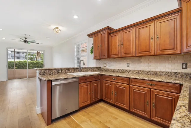 a kitchen with stainless steel appliances granite countertop a stove a sink dishwasher and a microwave oven with wooden floor