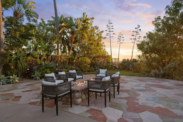 a view of a patio with couches and a table and chairs under an umbrella with a fire pit and a fire pit
