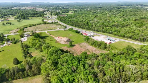 an aerial view of a residential houses with outdoor space and trees all around