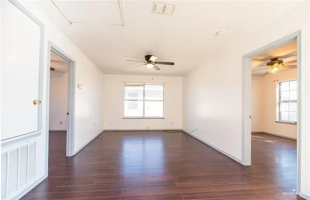 an empty room with wooden floor and windows