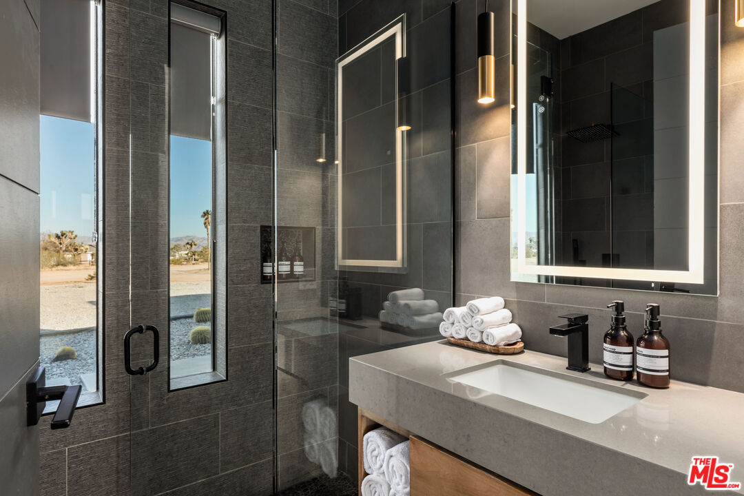 3000 Rockwood Road Joshua Tree, CA 92252 - Photo 25 of 71 a bathroom with a granite countertop sink a mirror and shower