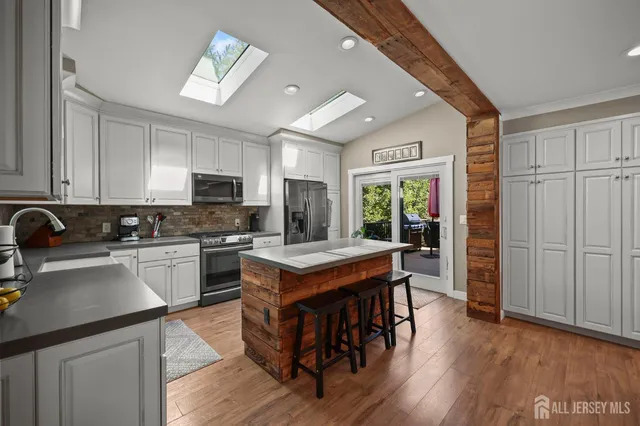 a kitchen with a stove a refrigerator and a view of living room