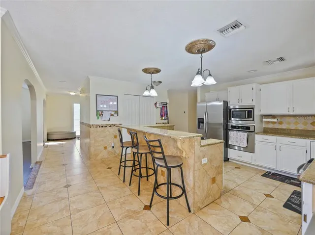 a dining hall with granite countertop a sink cabinets and chandelier