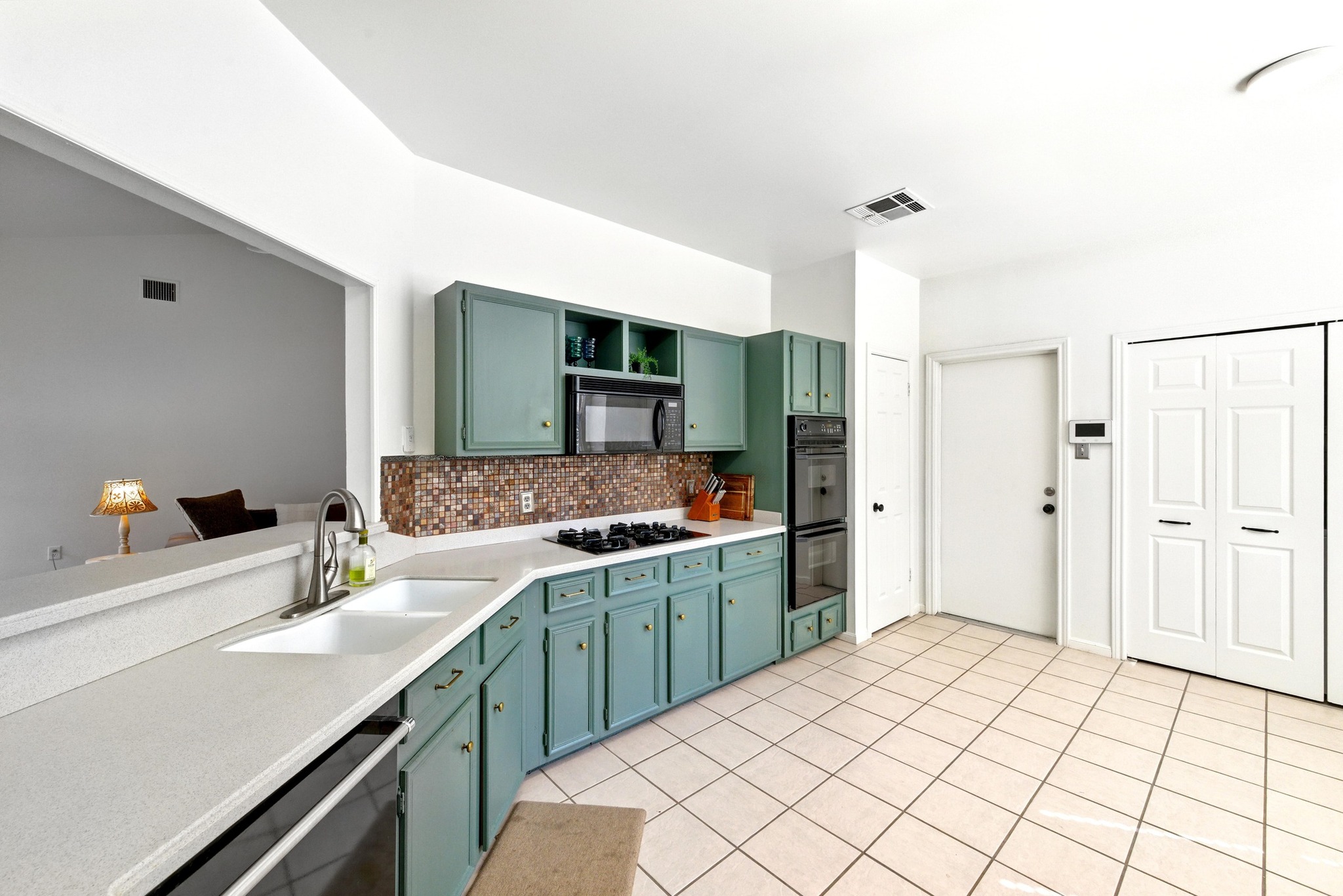 5807 Convict Hill Road Austin, TX 78749 - Photo 10 of 27 This spacious kitchen features stylish green cabinetry, a sleek gas cooktop, and a mosaic tile backsplash with tons of storage. The passthrough window opens to the living room for easy entertaining.