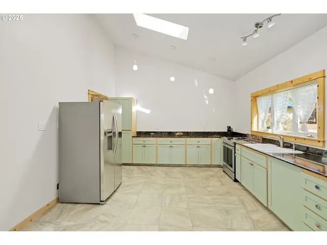 a large white kitchen with a sink and large window