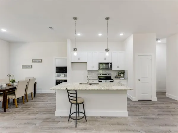 a large kitchen with kitchen island a dining table chairs and a wooden floor