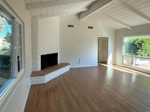 a view of empty room with wooden floor and fireplace