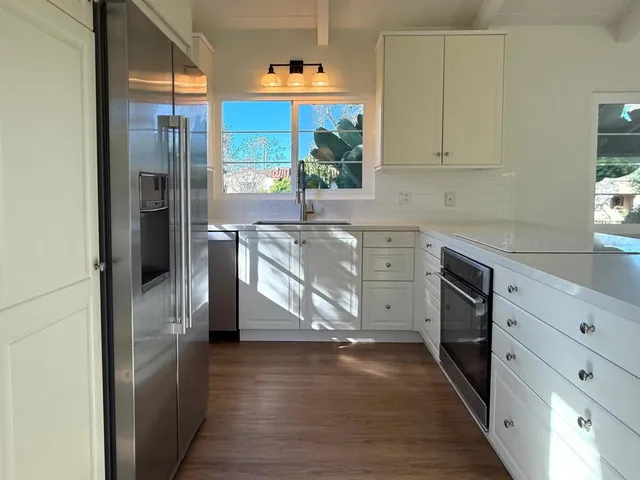 a kitchen with stainless steel appliances granite countertop a refrigerator a sink and white cabinets