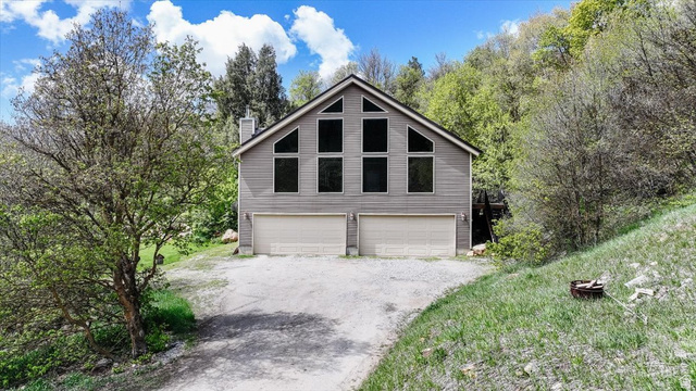 7203 East Cub River Road Preston, ID 83263 - Photo 28 of 33 View of front facade featuring a chimney, a garage, and driveway