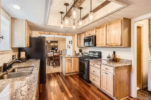 a kitchen with stainless steel appliances granite countertop a stove top oven a sink dishwasher a refrigerator and cabinets with wooden floor