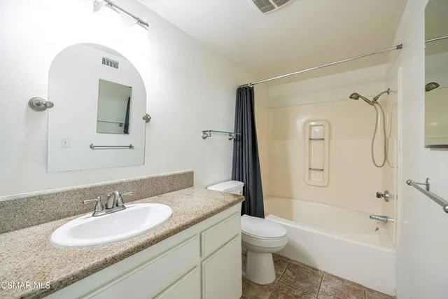 a bathroom with a granite countertop sink toilet and shower