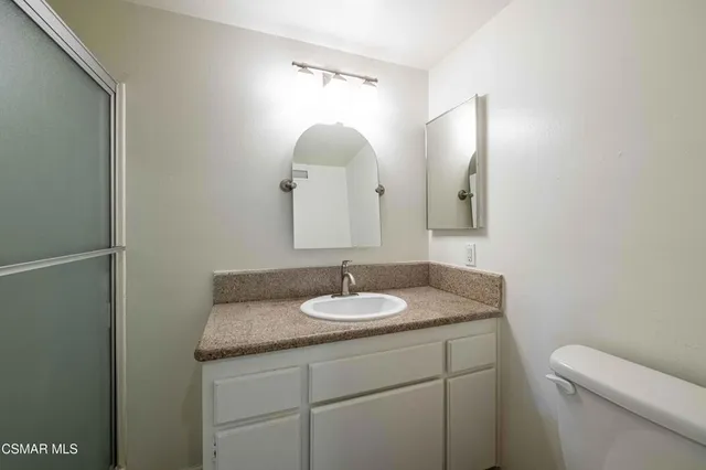 a bathroom with a granite countertop sink a toilet and a mirror