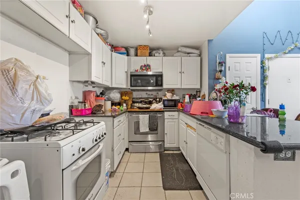 a kitchen with kitchen island a white stove top oven and sink with cabinets