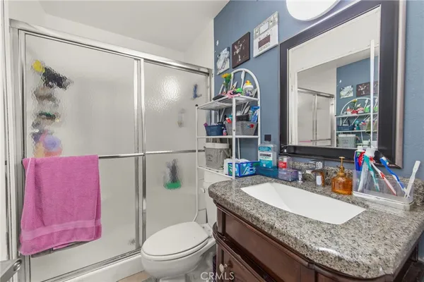 a bathroom with a granite countertop sink a toilet and shower