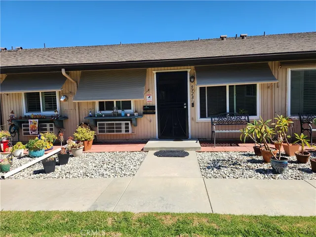 a view of a house with potted plants and a bench