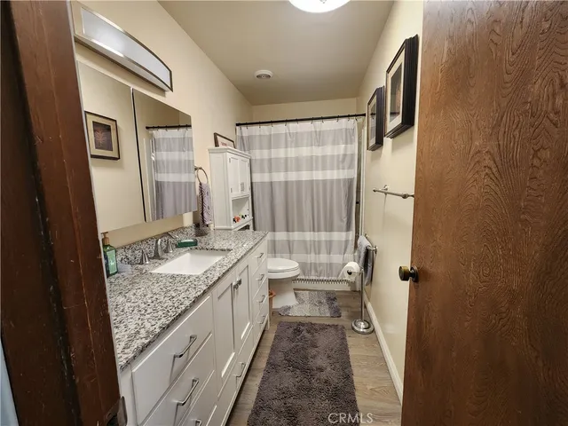 a bathroom with a granite countertop sink a toilet and shower