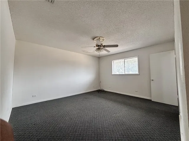 an empty room with a chandelier fan and windows