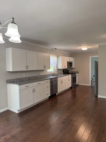 a kitchen with granite countertop a sink cabinets and wooden floor