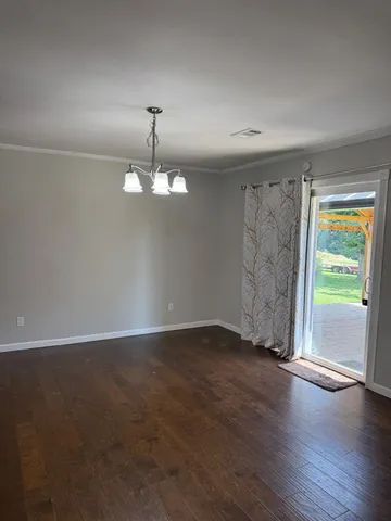 an empty room with wooden floor chandelier fan and windows