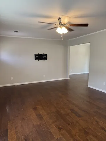 an empty room with wooden floor chandelier fan and windows