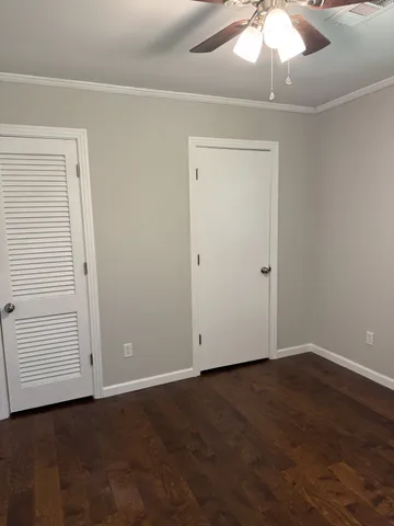 an empty room with wooden floor closet and windows
