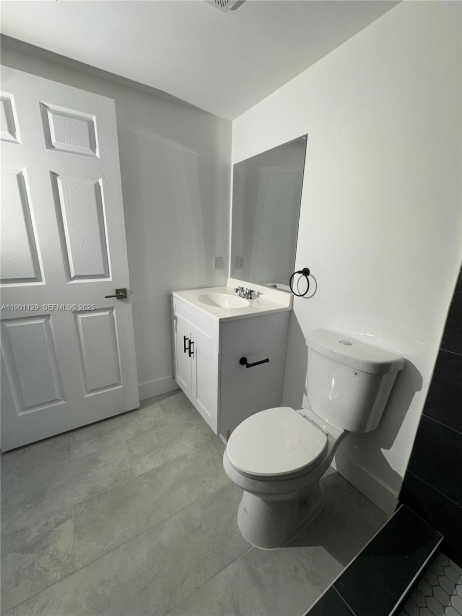 147 Northwest 59th Street, Unit 203 Miami, FL 33127 - Photo 9 of 12 a white toilet sitting next to a bathroom sink