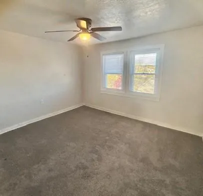 an empty room with windows and fan