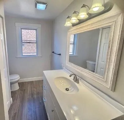 a bathroom with a granite countertop sink a toilet a mirror and shower