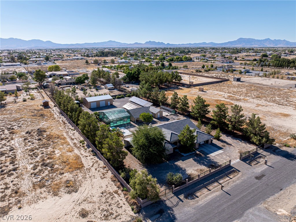 3780 South Ranger Way Pahrump, NV 89048 - Photo 55 of 57 An aerial perspective reveals a spacious estate featuring a large pool enclosure, ample parking, and distant mountain vistas.