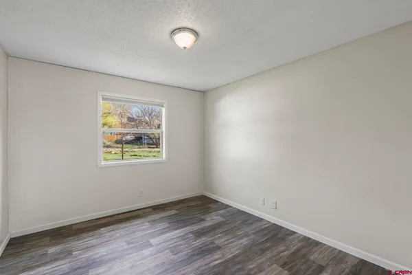 an empty room with wooden floor and window