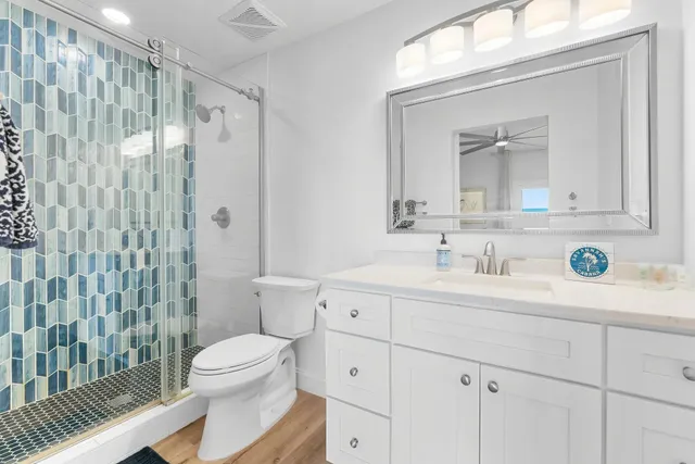 a bathroom with a granite countertop sink toilet a mirror a vanity and shower