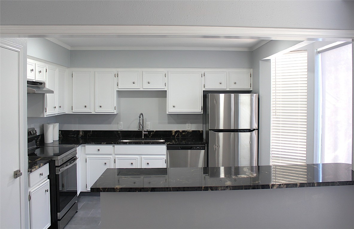 108 World Of Tennis Square, Unit 108C Lakeway, TX 78738 - Photo 6 of 25 a kitchen with kitchen island granite countertop a refrigerator a sink and white cabinets