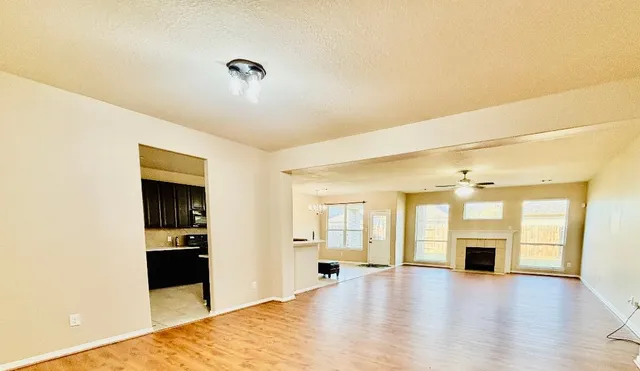 a view of an empty room with window and chandelier fan